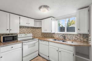 Kitchen with open shelves, white appliances, white cabinets, tasteful backsplash, and a textured ceiling