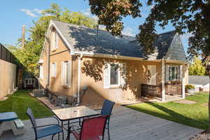 Rear view of house with a wooden deck, roof with shingles, brick siding, and outdoor dining area