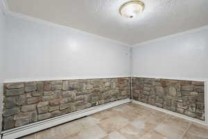 Unfurnished room with a baseboard radiator, a textured ceiling, and ornamental molding