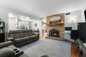 Living room with a fireplace, wood finished floors, an office area, and a chandelier