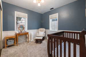 Carpeted bedroom with a nursery area, a textured ceiling, and a baseboard heating unit