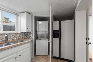 Laundry area featuring stacked washing machine and dryer and a textured ceiling