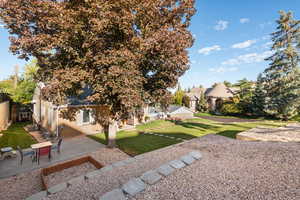 View of green lawn with a wooden deck and a patio area