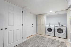Laundry area featuring washing machine and clothes dryer and a textured ceiling
