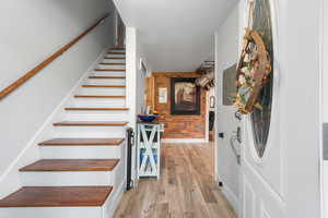 Stairs with wood finished floors, brick wall, and electric panel