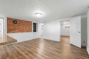 Unfurnished room with wood finished floors, a textured ceiling, and built in features