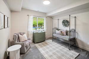 Carpeted bedroom with a crib and baseboards