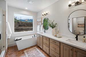 Bathroom featuring double vanity, a freestanding bath, light tile patterned flooring, a baseboard heating unit, and an enclosed shower