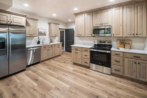 Kitchen with stainless steel appliances, recessed lighting, light wood-style flooring, light stone countertops, and light brown cabinets