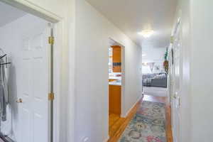 Hallway featuring light wood-style flooring and a textured ceiling