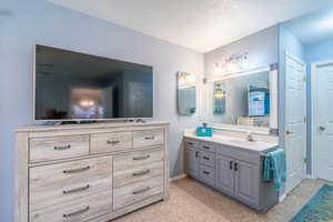 Bathroom featuring two vanities, light colored carpet, and a textured ceiling