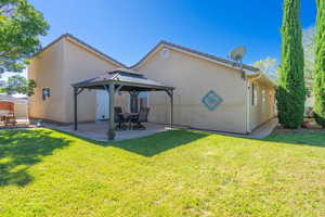 Rear view of property featuring a gazebo, a patio, stucco siding, and a yard