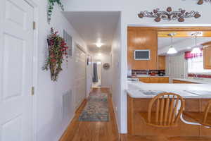 Kitchen with light countertops, light wood-style floors, a peninsula, hanging light fixtures, and brown cabinetry