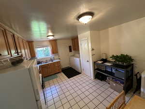 Kitchen featuring white refrigerator, brown cabinetry, light countertops, and light tile patterned flooring