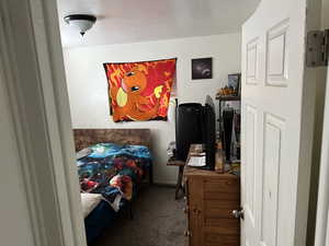 Carpeted bedroom with a textured ceiling and baseboards