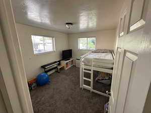 Bedroom featuring dark carpet and a textured ceiling