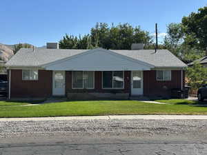 View of front facade with brick siding, a front lawn, and a shingled roof