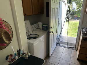 Laundry room featuring light tile patterned flooring, cabinet space, and washer and dryer