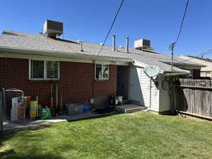 Back of house with a shingled roof and brick siding