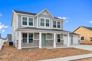 Craftsman-style house with board and batten siding, covered porch, concrete driveway, and stone siding