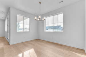 Empty room featuring a chandelier and light wood-style flooring