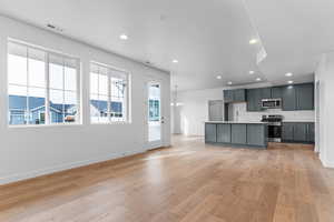 Kitchen featuring light countertops, recessed lighting, stainless steel appliances, open floor plan, and an island with sink