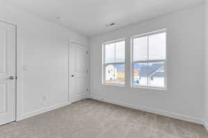 Unfurnished bedroom with baseboards and light colored carpet
