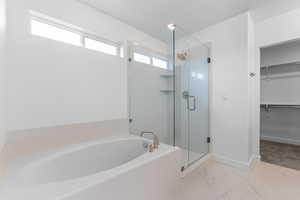 Bathroom featuring a bath, a shower stall, marble finish flooring, and a walk in closet