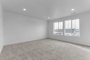 Empty room with light colored carpet and recessed lighting