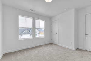 Unfurnished bedroom with light carpet and baseboards