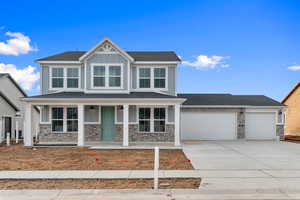 Craftsman house with a porch, concrete driveway, an attached garage, stone siding, and board and batten siding