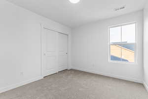 Unfurnished bedroom with light colored carpet and a closet