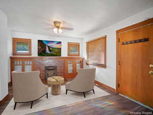 Living area with a tile fireplace, wood finished floors, a ceiling fan, and a textured ceiling