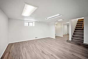 Below grade area featuring light wood-type flooring and stairway