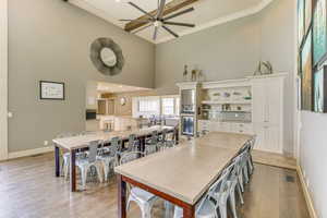 Dining room with a towering ceiling, light wood-style flooring, recessed lighting, ceiling fan, and ornamental molding