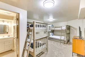 Bedroom featuring a textured ceiling, light carpet, and connected bathroom