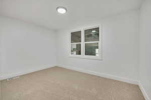 Spare room featuring baseboards and light carpet