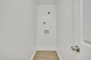 Washroom with light wood-style floors, hookup for a washing machine, and electric dryer hookup
