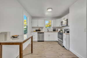Kitchen with light countertops, stainless steel appliances, light wood-style floors, and healthy amount of natural light