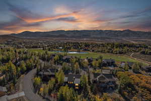 Aerial overview of property's location with a water and mountain view, a local golf course, and nearby suburban area