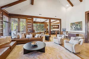 Living room with beam ceiling, high vaulted ceiling, wood finished floors, and a chandelier