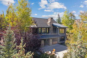 View of front of property featuring a metal roof, a standing seam roof, stone siding, and a chimney