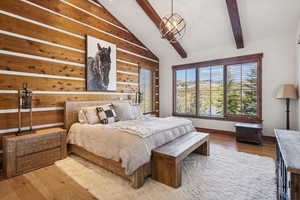 Bedroom with wood finished floors, wood walls, and a chandelier