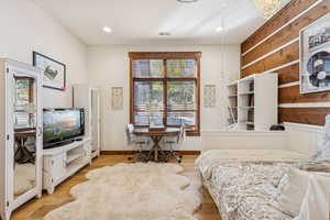 Bedroom with wood finished floors, wood walls, and recessed lighting