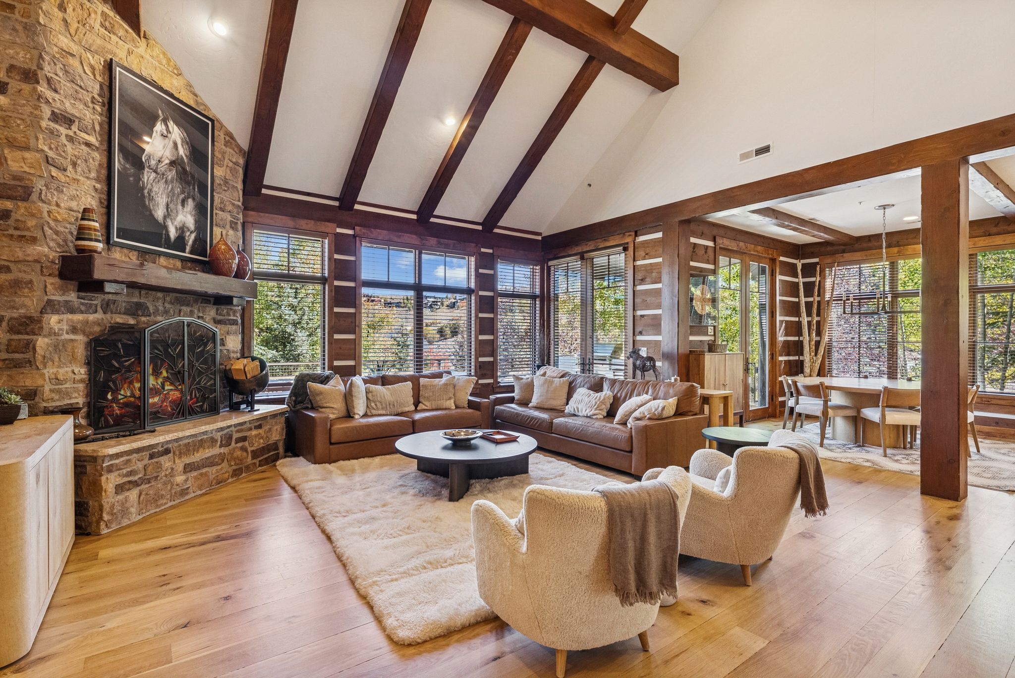 Living room featuring high vaulted ceiling, beam ceiling, light wood-style flooring, and a fireplace