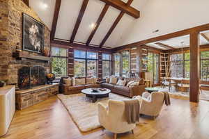 Living room featuring high vaulted ceiling, beam ceiling, light wood-style flooring, and a fireplace