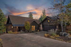 Rustic home with stone siding, concrete driveway, and an attached garage