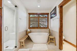 Full bath with a soaking tub, a marble finish shower, tile walls, tile patterned flooring, and recessed lighting