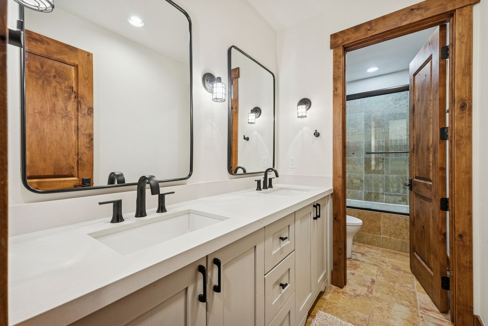 Bathroom featuring tiled shower / bath, double vanity, recessed lighting, and stone tile floors