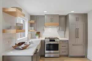 Kitchen with gray cabinets, open shelves, gas stove, decorative backsplash, and recessed lighting